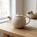 AI-generated concept image of an ivory teapot on a light oak table
